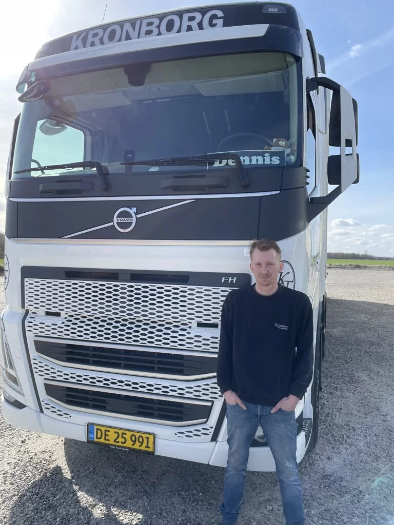 Mand foran stor lastbil med blå himmel