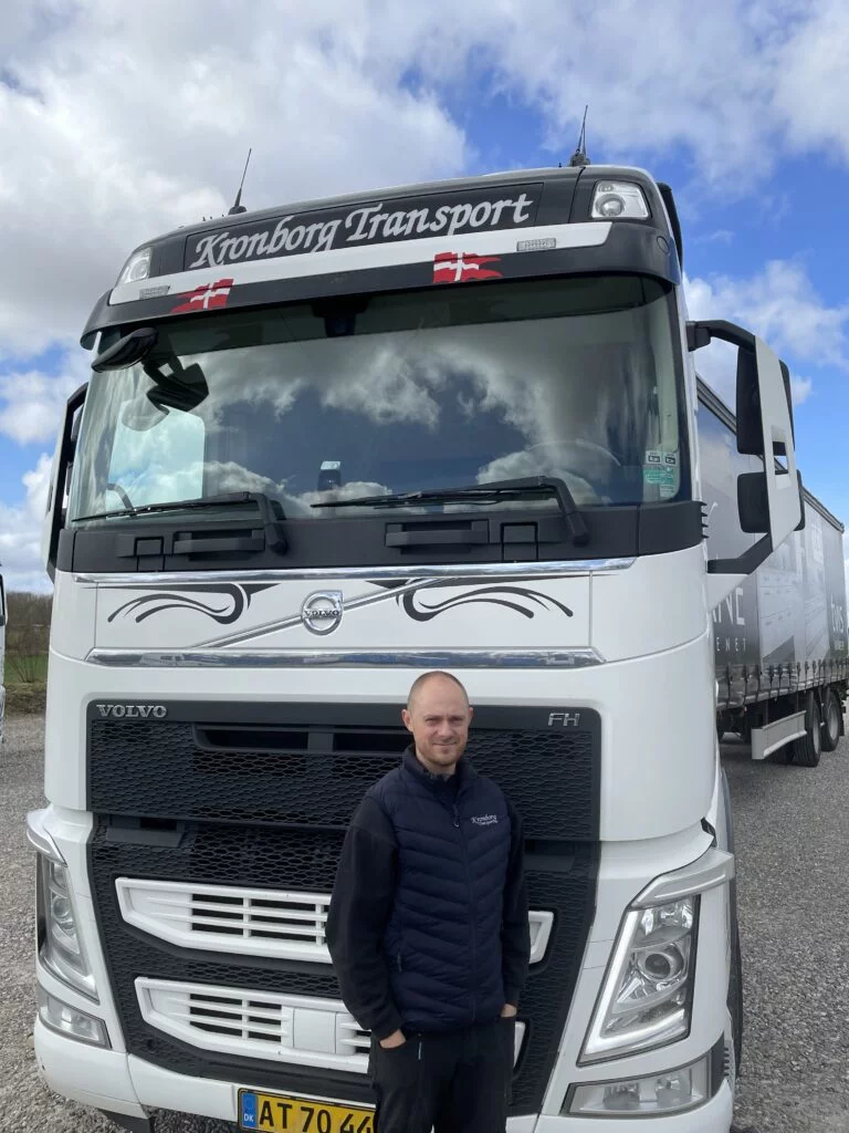 Chauffør foran Kronborg Transport lastbil på grusvej.
